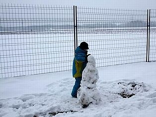 Ein Kind baut einen Schneemann am Modellflugplatz